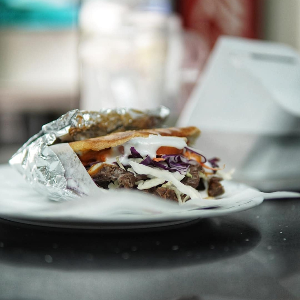 A Baba's Kebab with meat, red and white cabbage, and white sauce, wrapped in foil.
